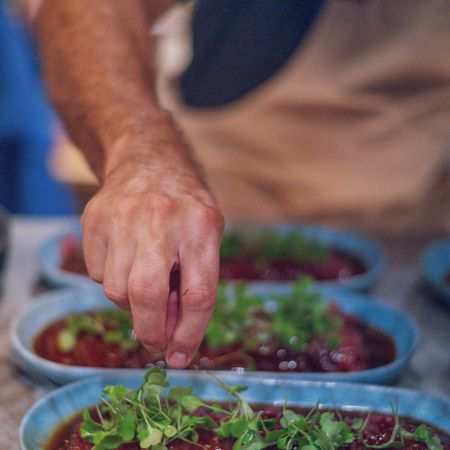 A close up of a person 's hand reaching into a bowl of food.