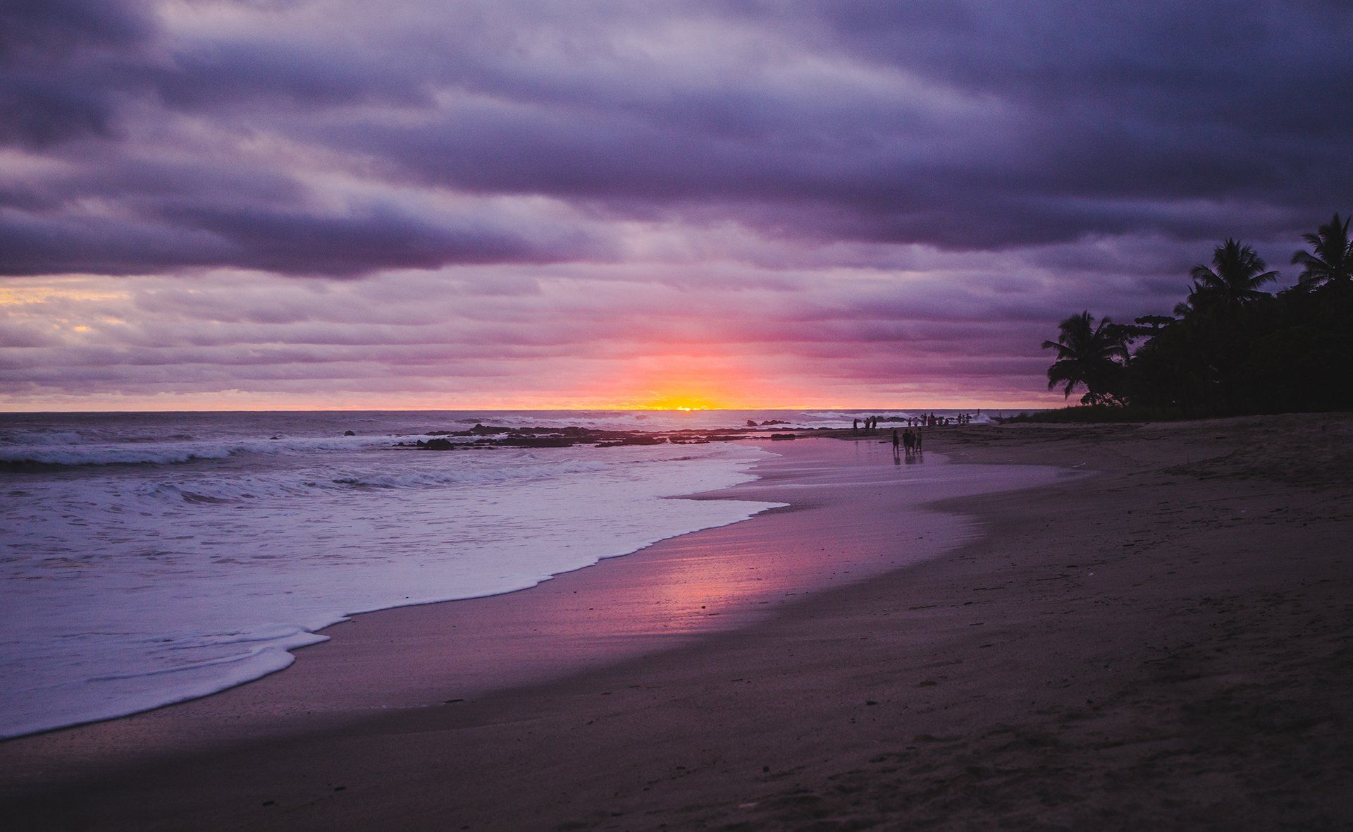 A person is walking on a beach at sunset.