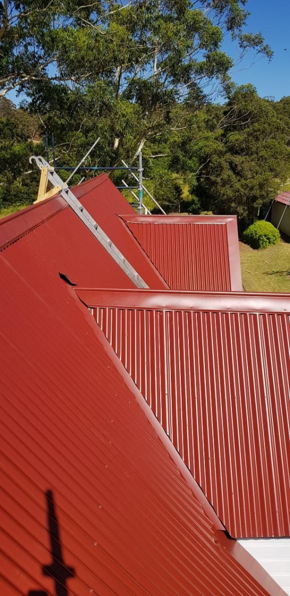 A Close Up Of A Red Roof With Trees In The Background — Glenroofing Pty Ltd In Taree, NSW