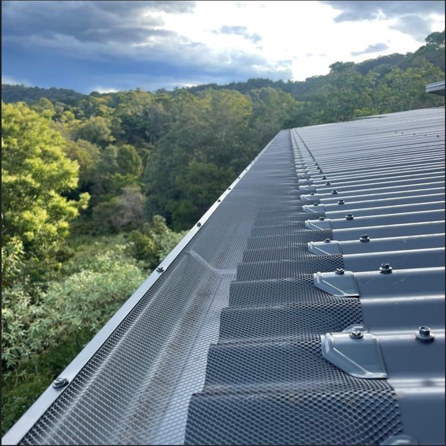 A Man Is Installing A Gutter On The Side Of A House — Glenroofing Pty Ltd In Taree, NSW