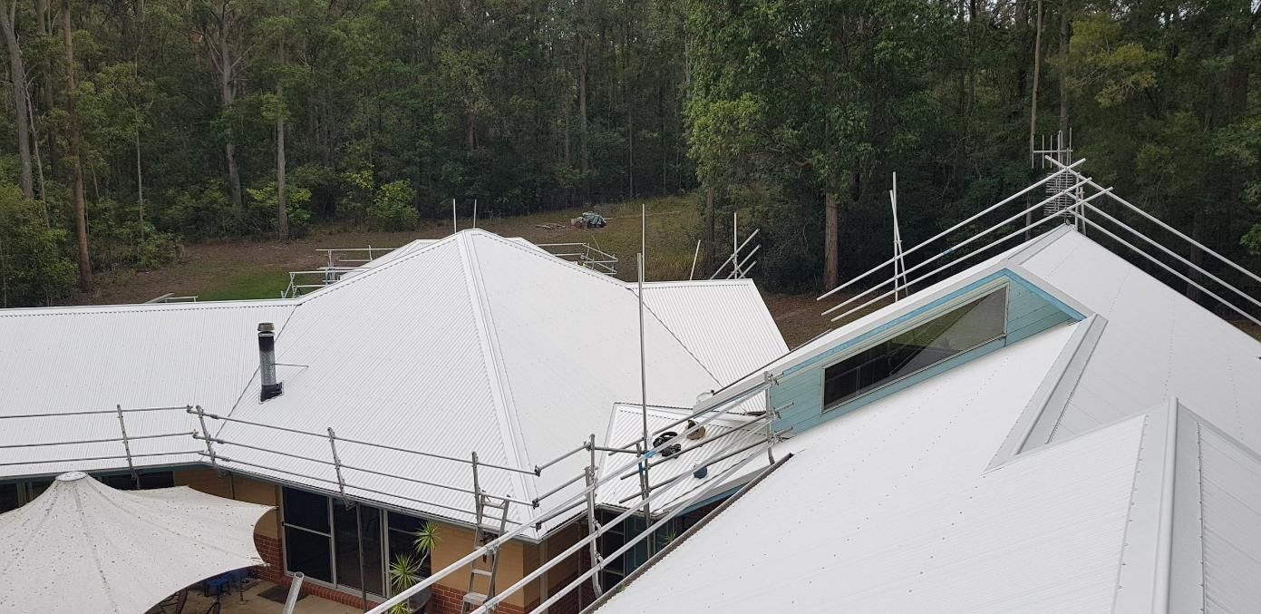 An Aerial View Of A House With A White Roof Surrounded By Trees — Glenroofing Pty Ltd In Taree, NSW