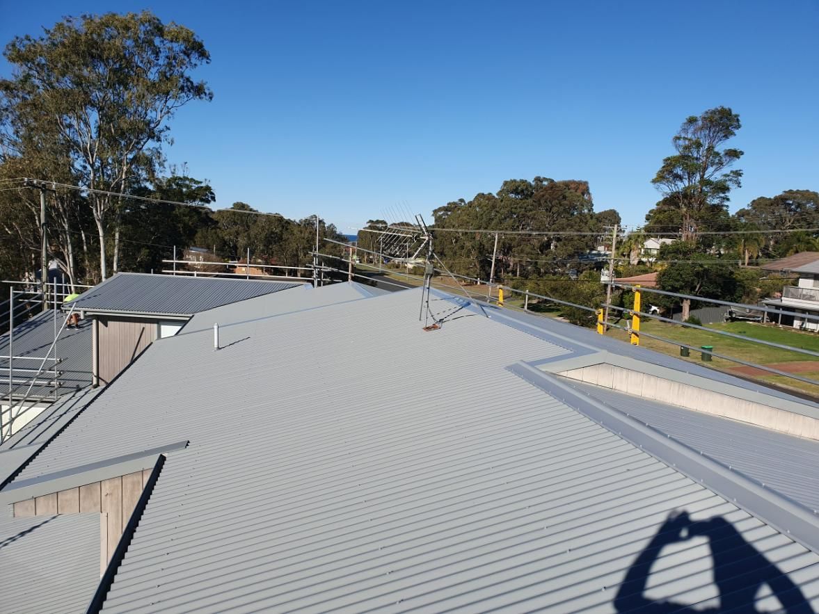 A Shadow Of A Person Is Cast On The Roof Of A Building — Glenroofing Pty Ltd In Coffs Harbour, NSW