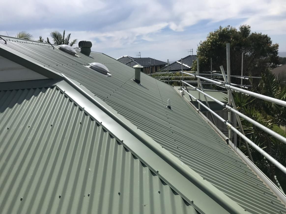 A Green Corrugated Metal Roof With Scaffolding On It — Glenroofing Pty Ltd In Taree, NSW