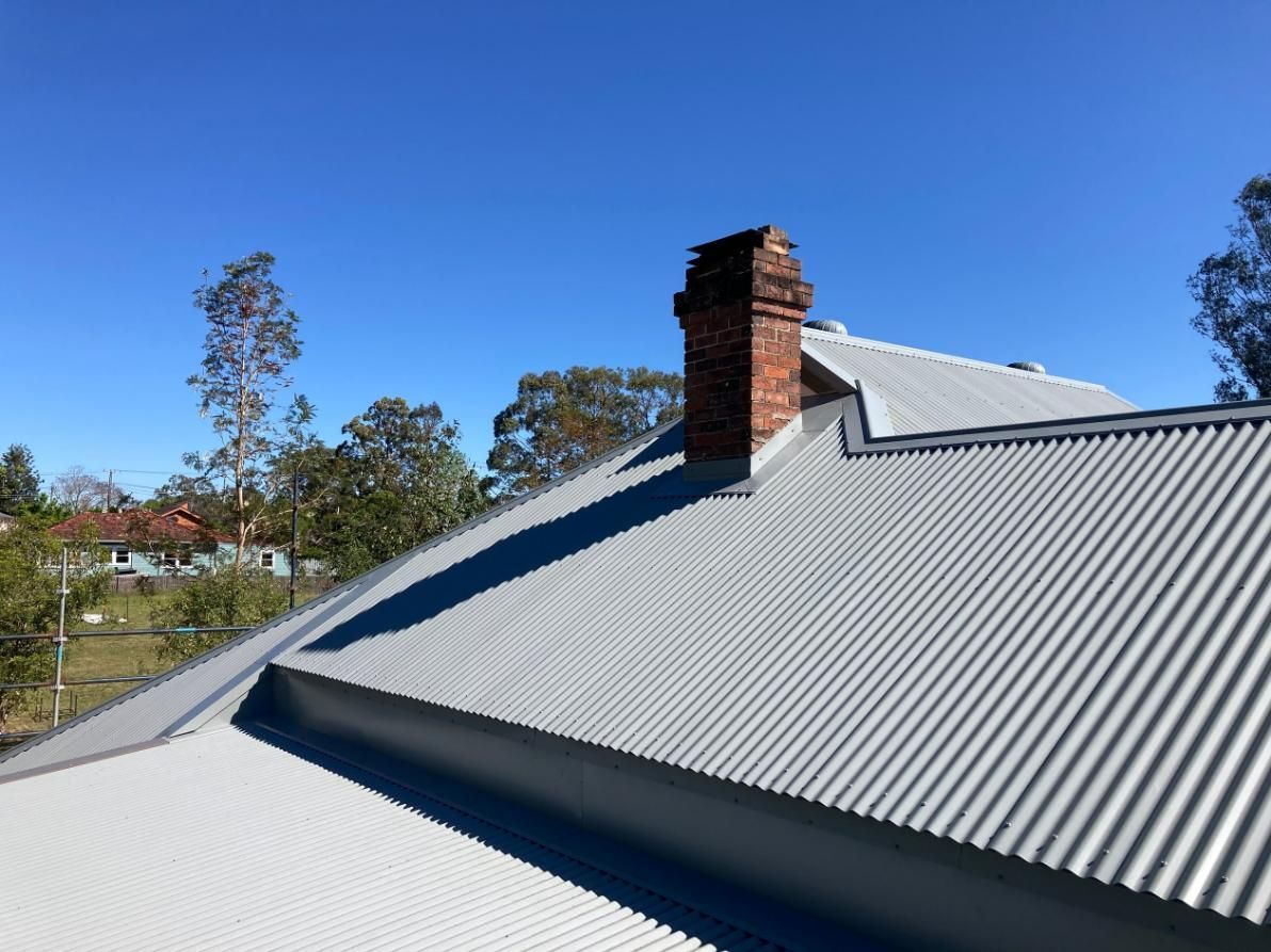 A Roof With A Chimney On It And A Blue Sky In The Background — Glenroofing Pty Ltd In Taree, NSW