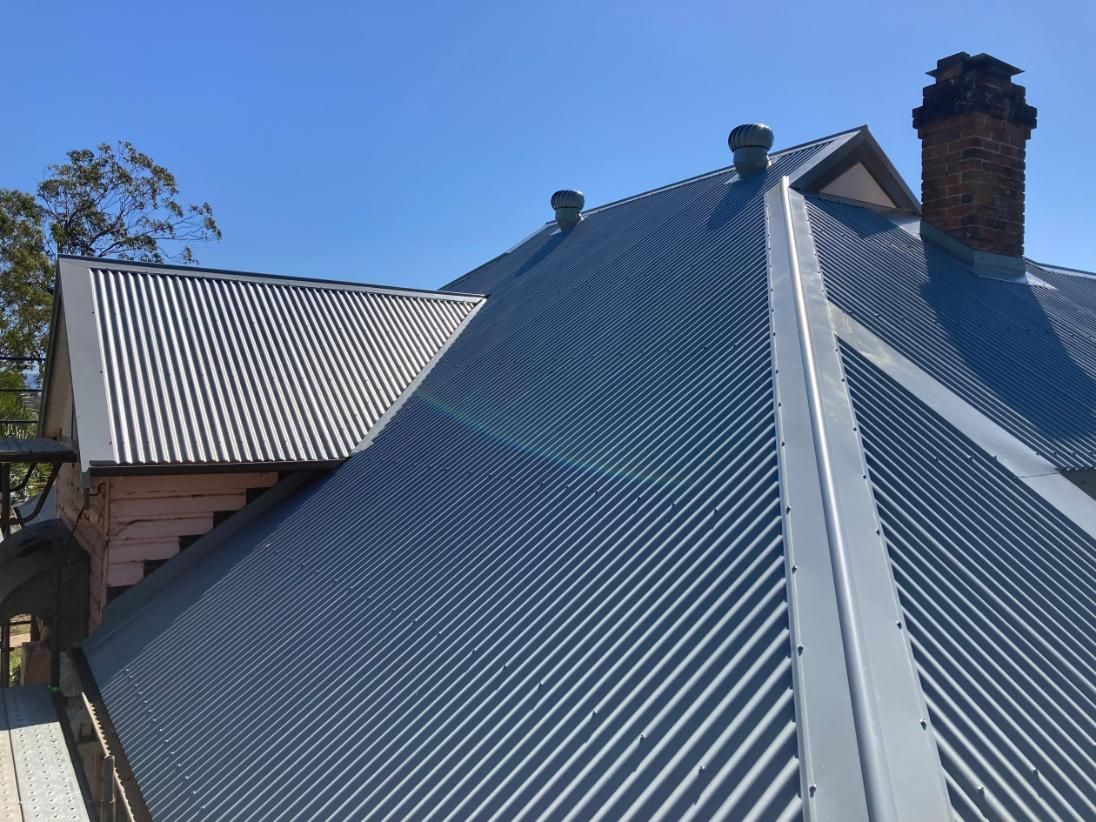 A Roof With A Chimney On Top Of It And A Blue Sky In The Background — Glenroofing Pty Ltd In Taree, NSW