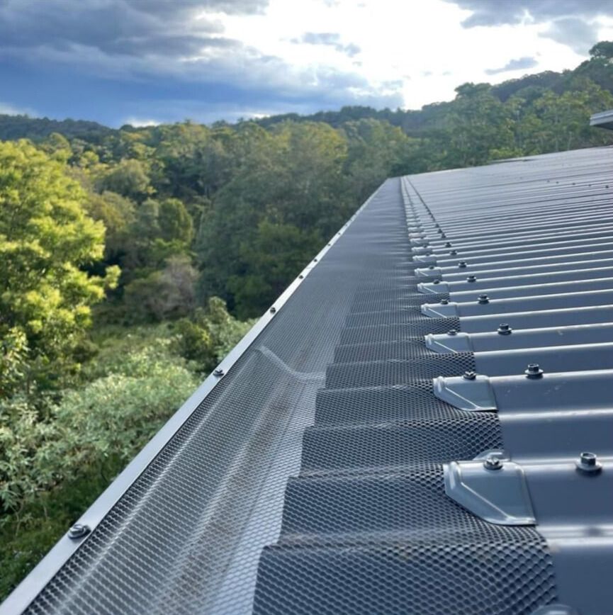 A Man Is Installing A Gutter On The Side Of A House — Glenroofing Pty Ltd In Taree, NSW