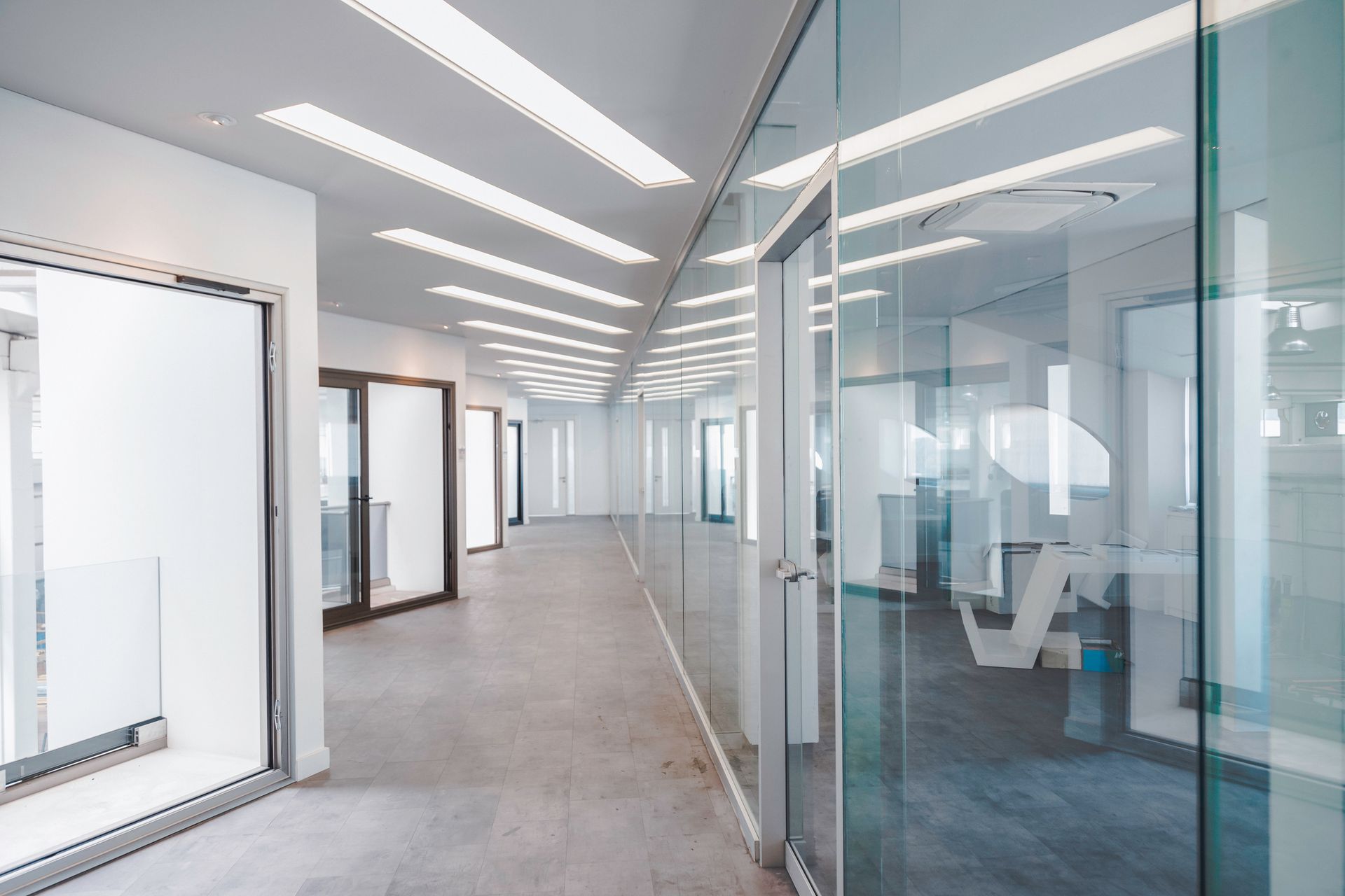 A long hallway with glass walls and doors in an office building.