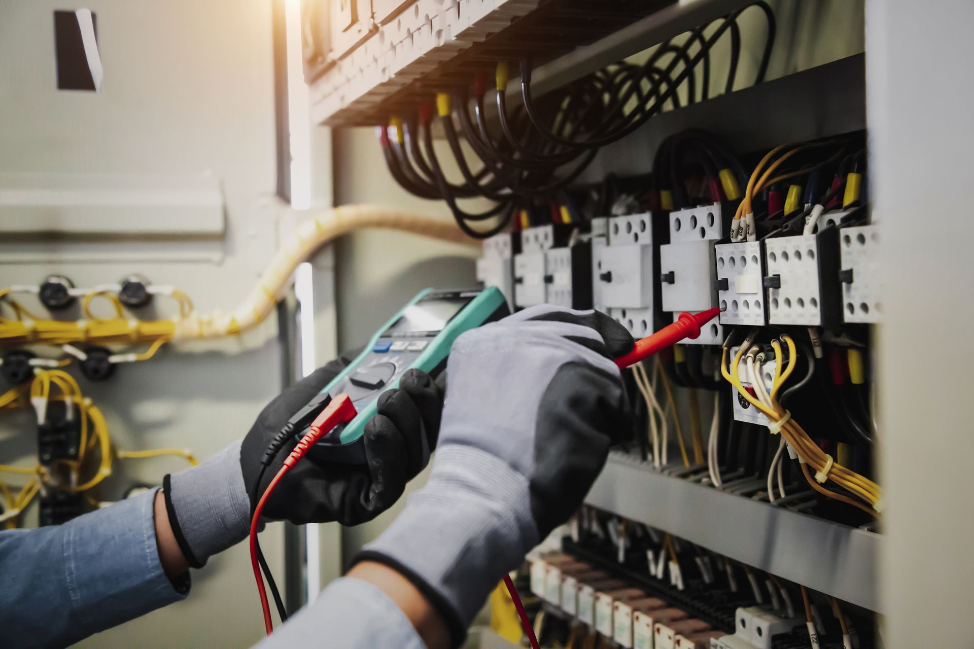An electrician is using a multimeter to test a circuit board.