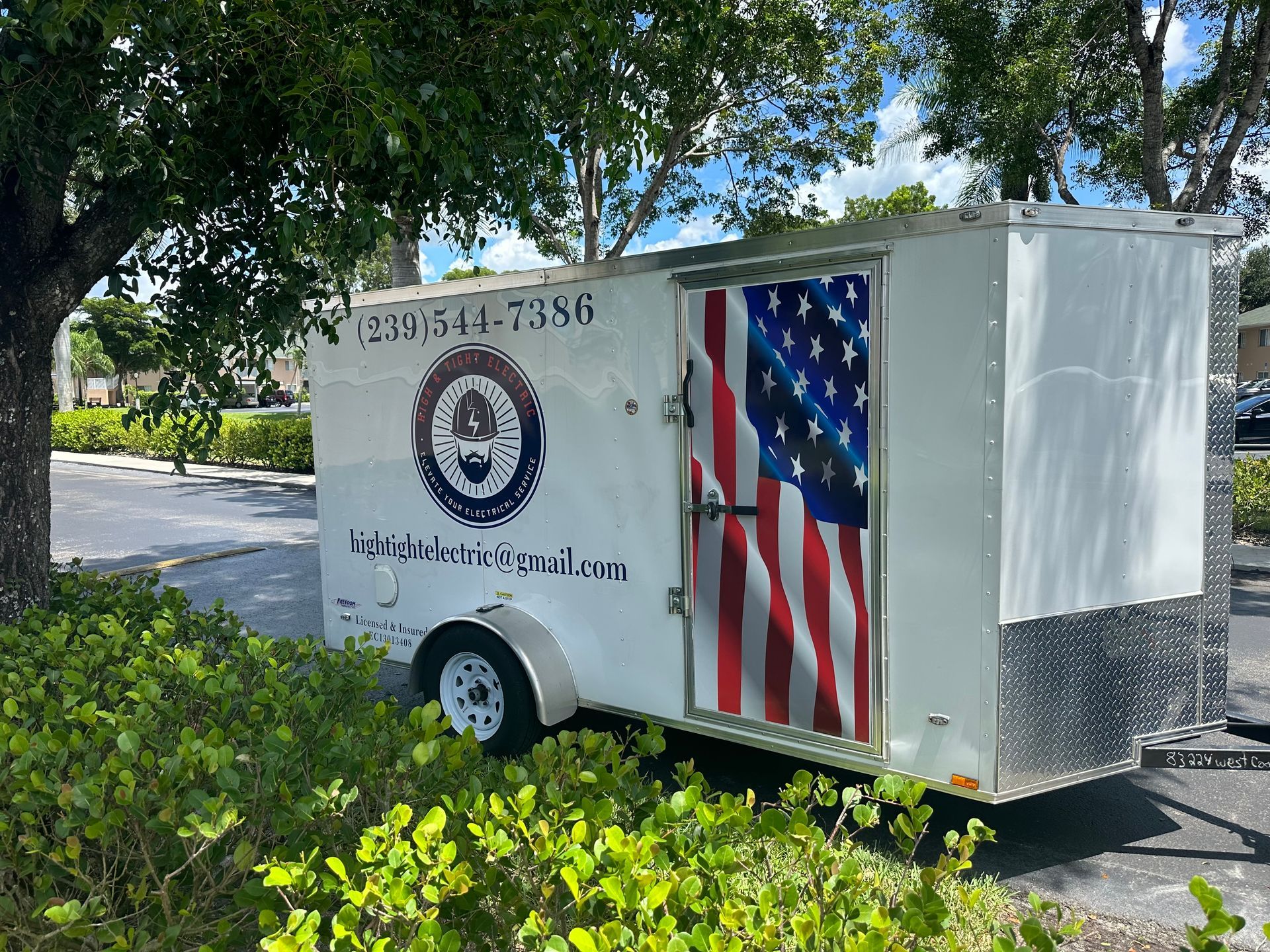 A white trailer with an american flag on the door is parked in a parking lot.
