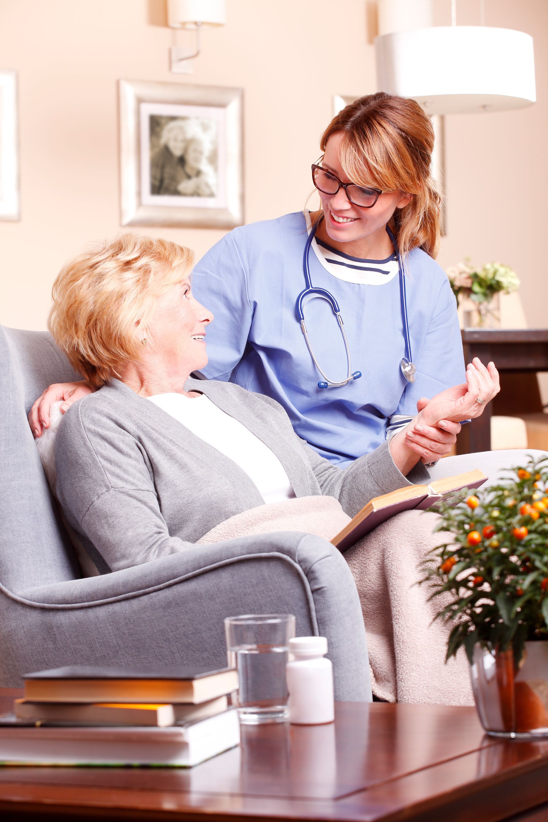 A nurse is talking to an elderly woman who is sitting in a chair.