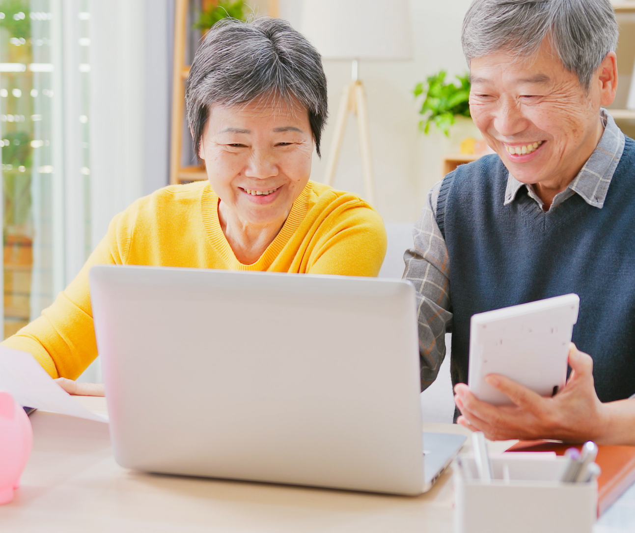 A man and a woman are sitting at a table looking at a laptop computer.