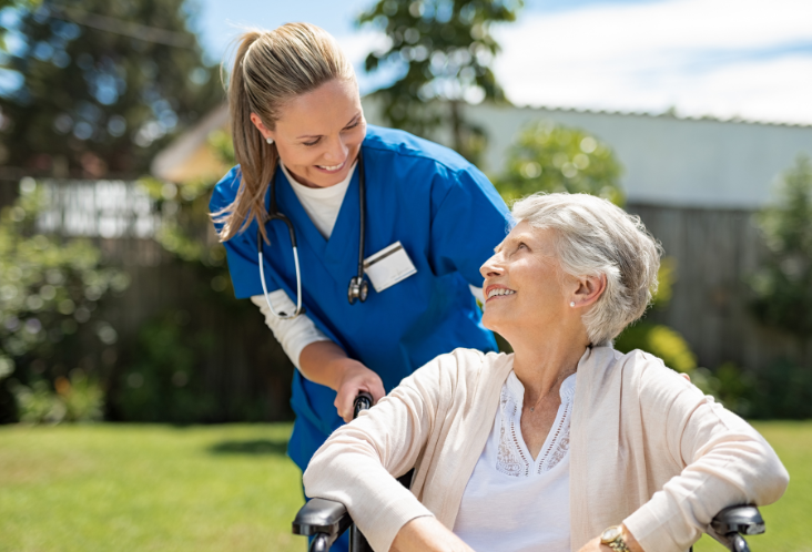 A nurse is helping an elderly woman in a wheelchair.