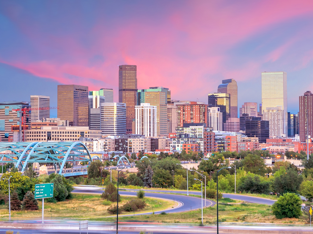 A city skyline at sunset with a bridge in the foreground.