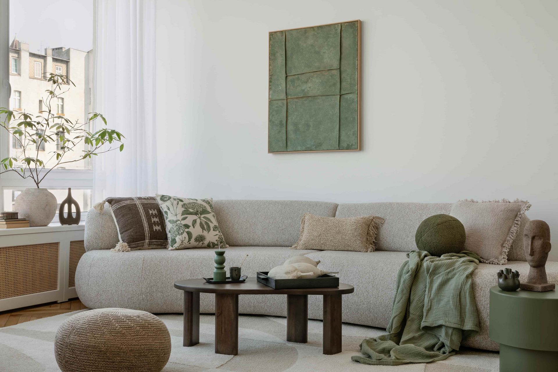 A modern living room with a curved, textured sofa, a wooden coffee table, a green wall art piece, and a green throw blanket.