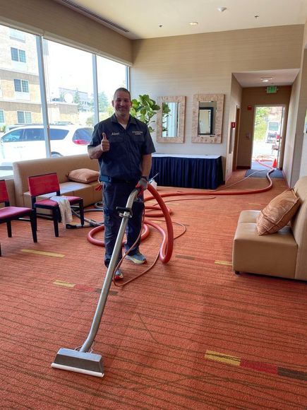 A man is using a vacuum cleaner to clean a carpet in a room.