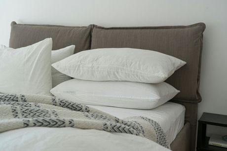 A bed with white sheets and pillows on it.