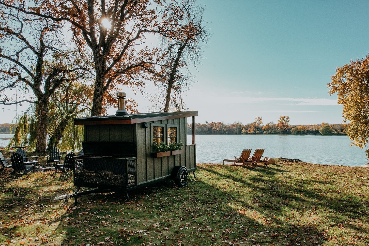 A trailer is parked in a grassy field next to a lake.