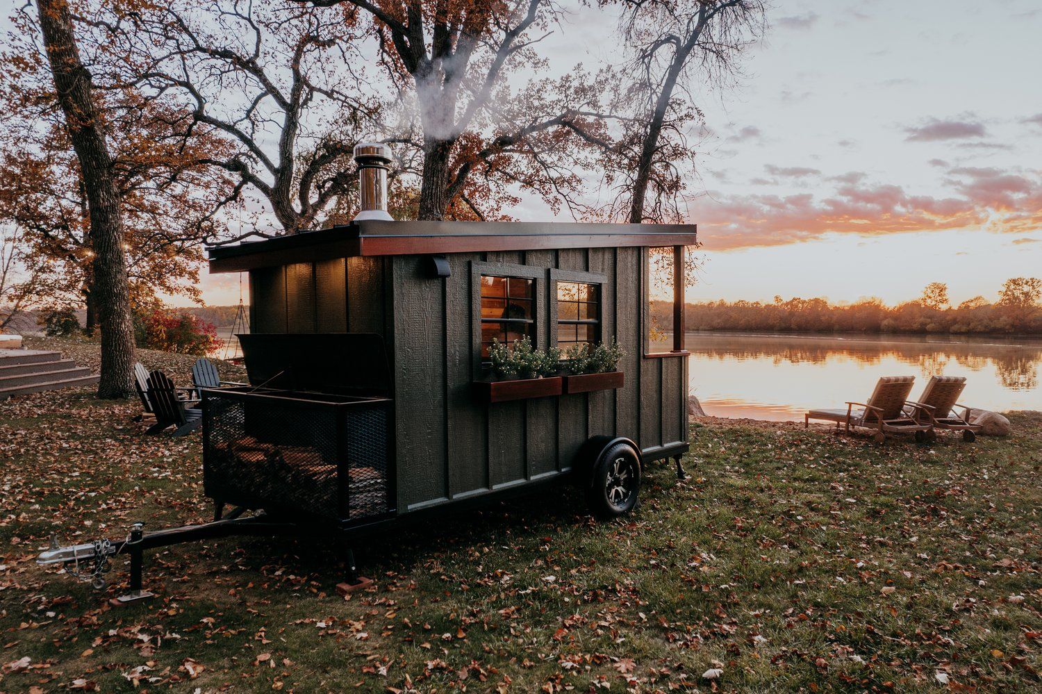 A small house on wheels is parked next to a lake.