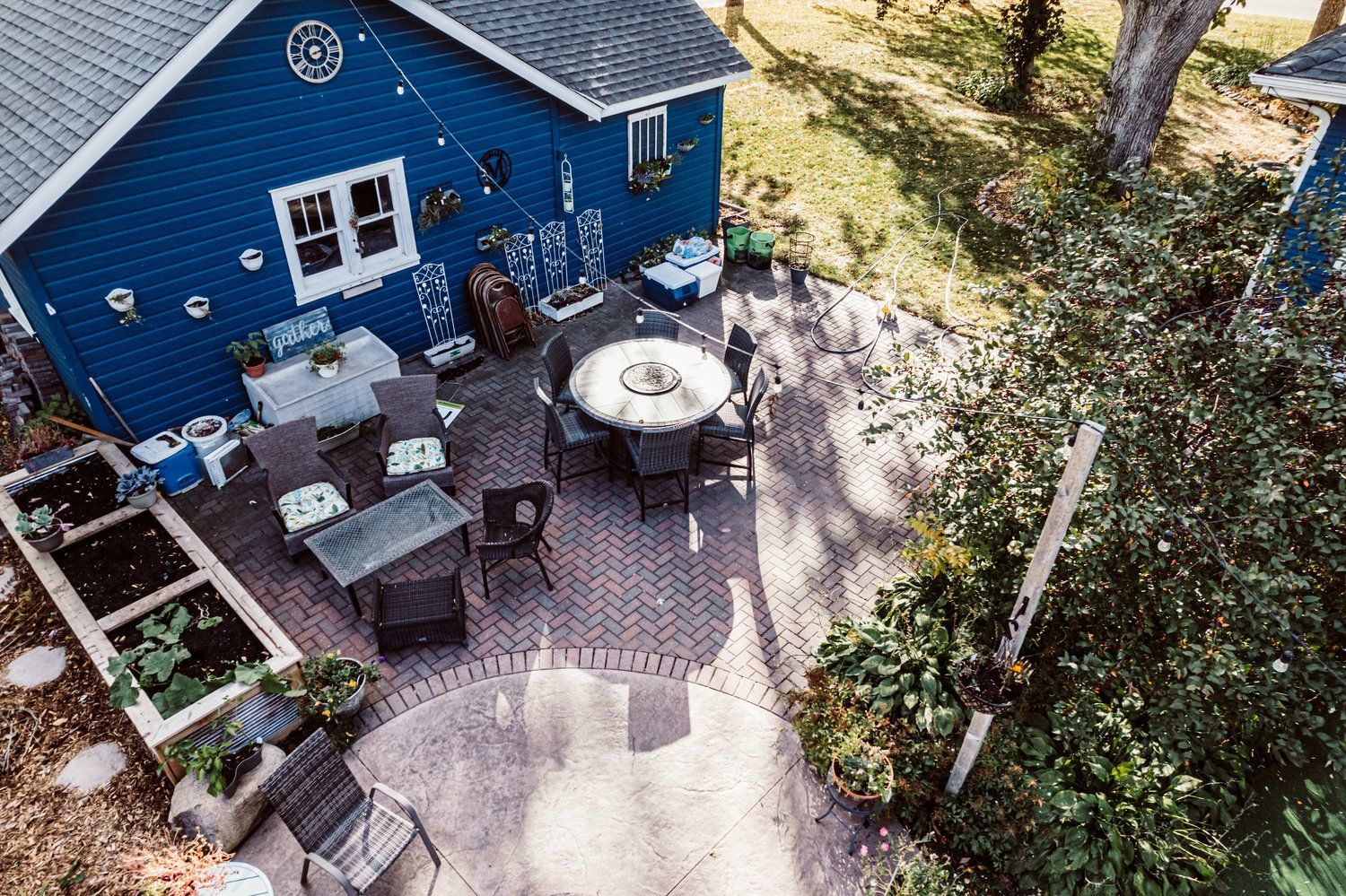 An aerial view of a blue house with a patio area with tables and chairs.