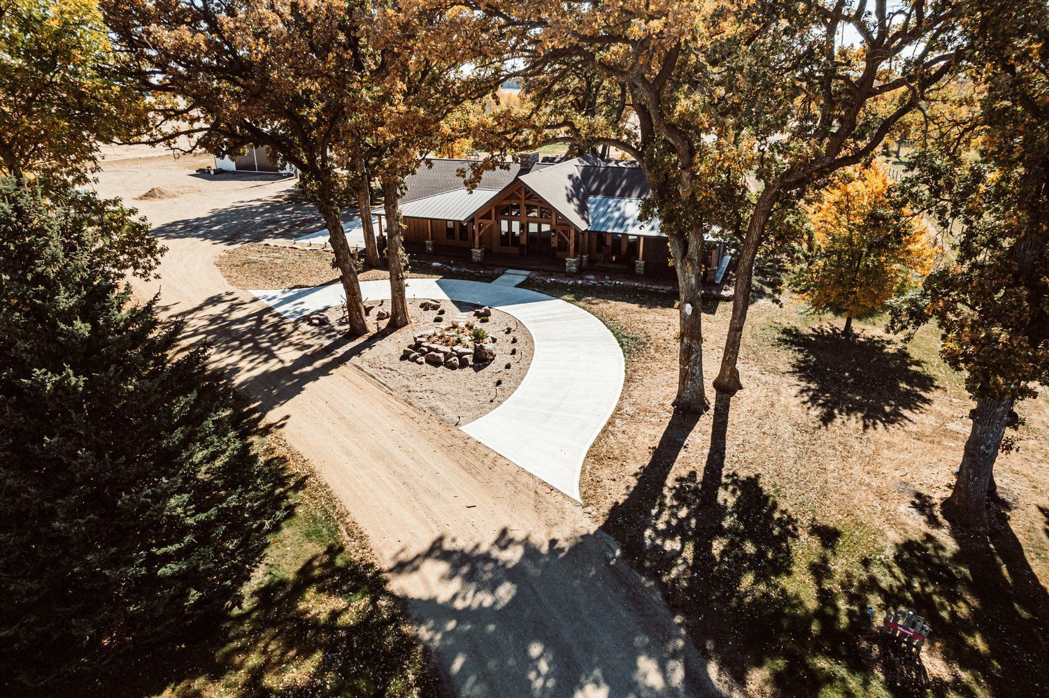 An aerial view of a house surrounded by trees and a dirt road.