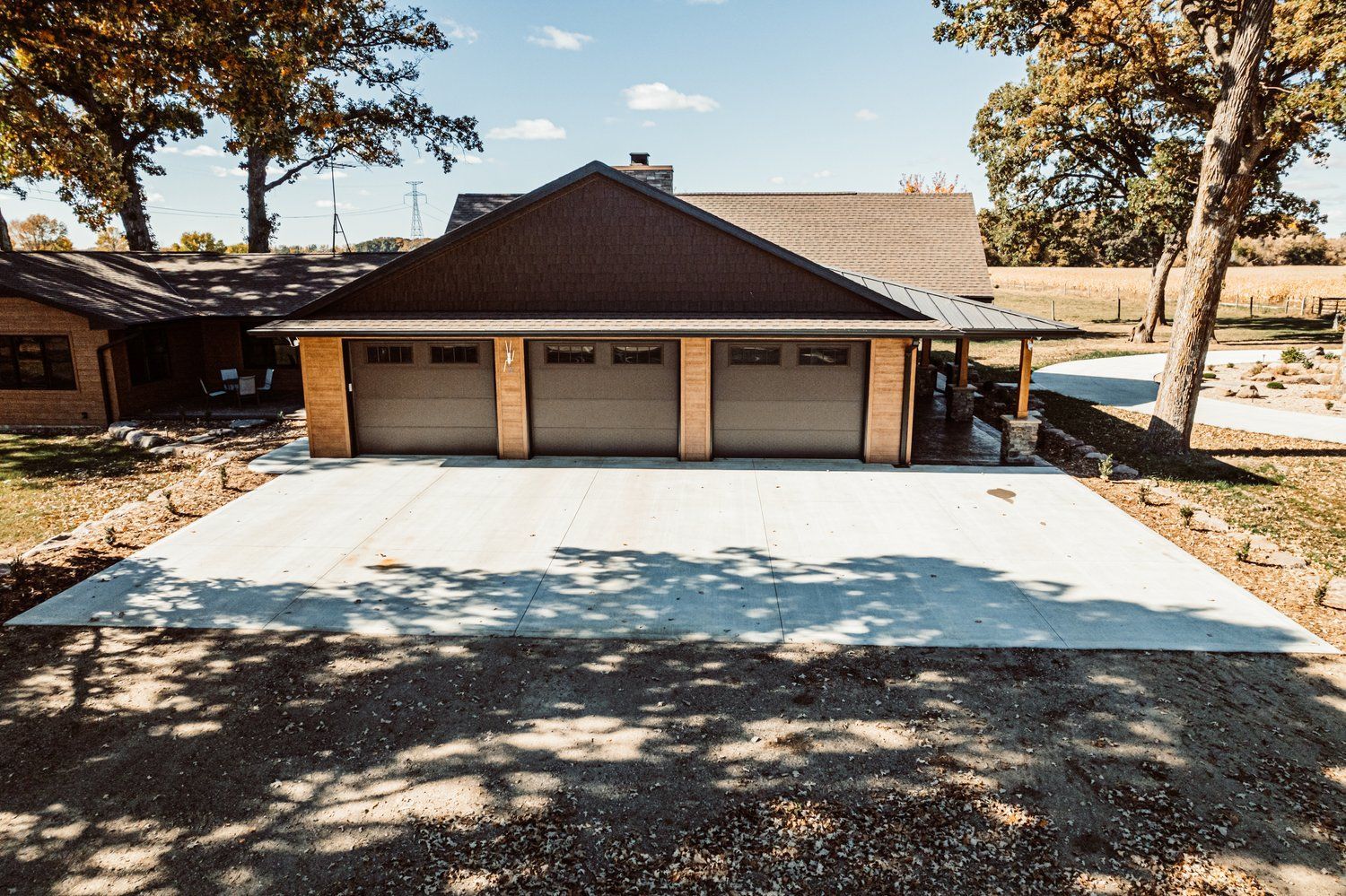 A large garage with three garage doors is sitting next to a house.