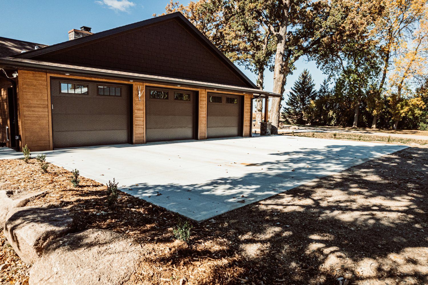 A house with three garage doors and a concrete driveway in front of it.