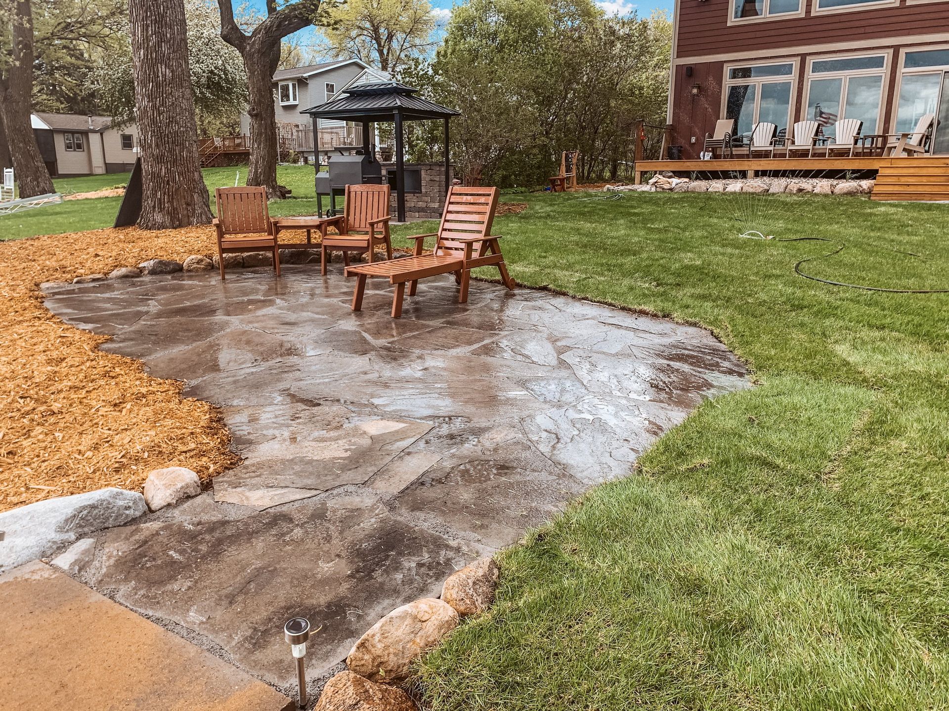 A patio with chairs and a table in front of a house.