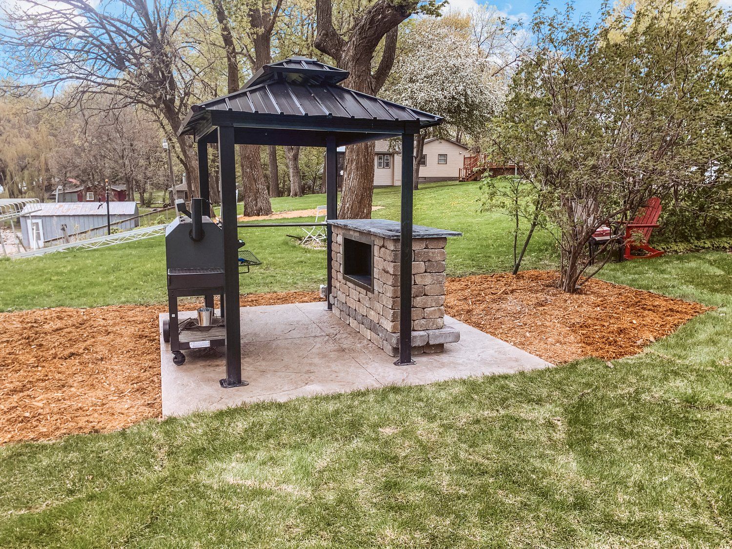 A gazebo with a grill and a fire pit in the backyard.