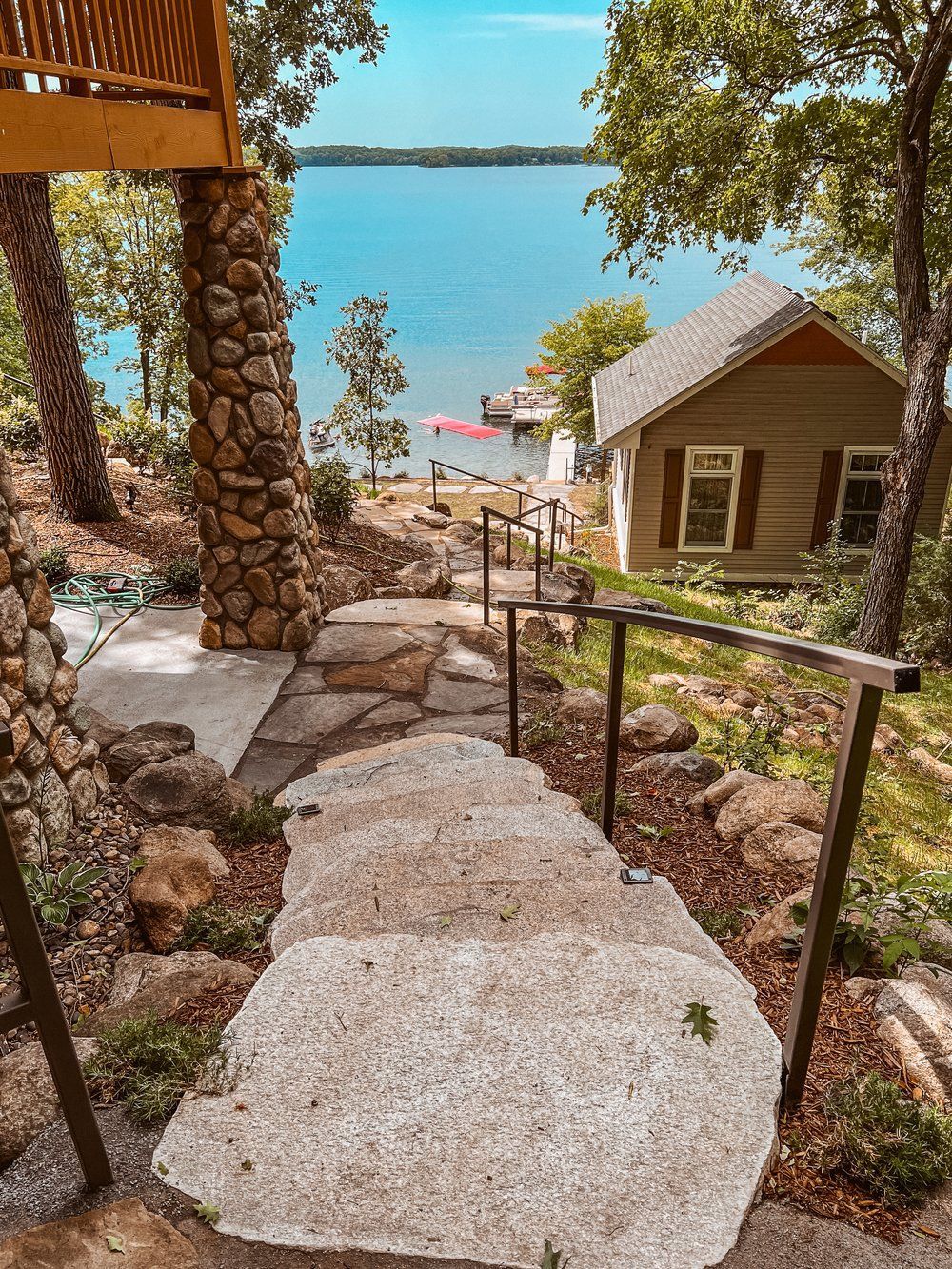 A stone walkway leading up to a house overlooking a lake.