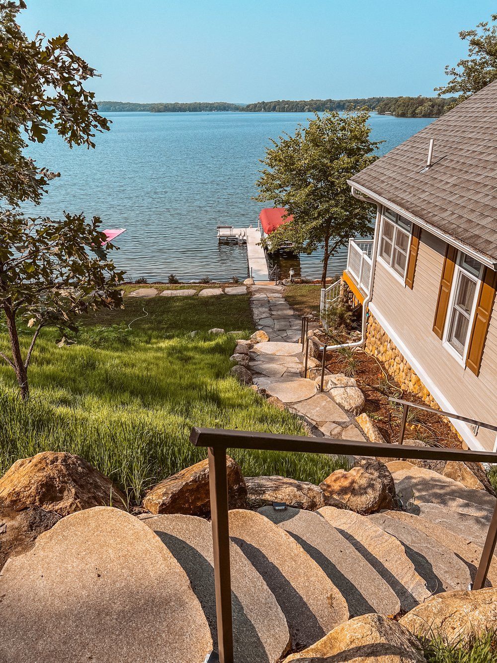 A house with stairs leading up to the water and a dock.