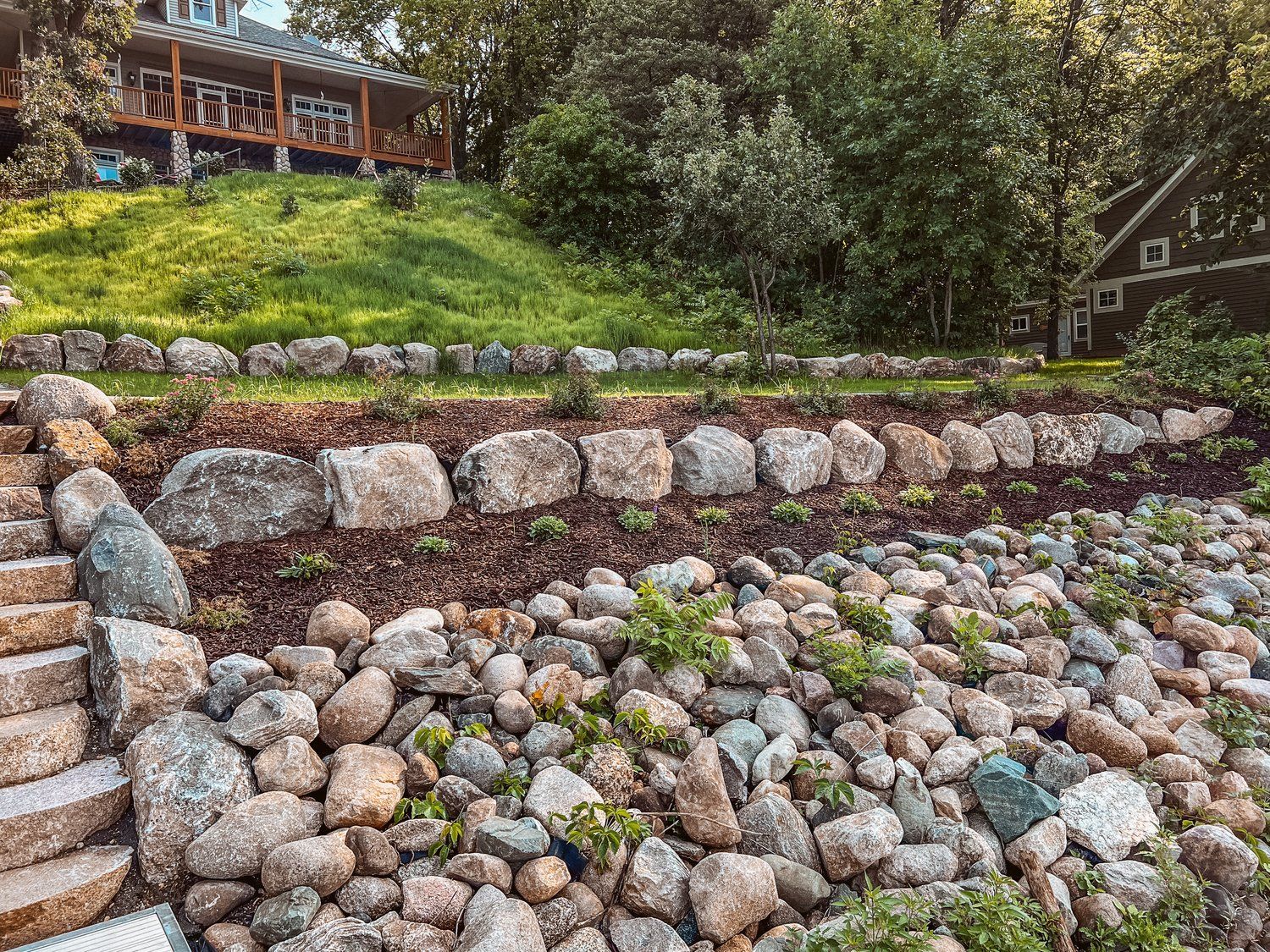There is a large pile of rocks in the foreground and a house in the background.