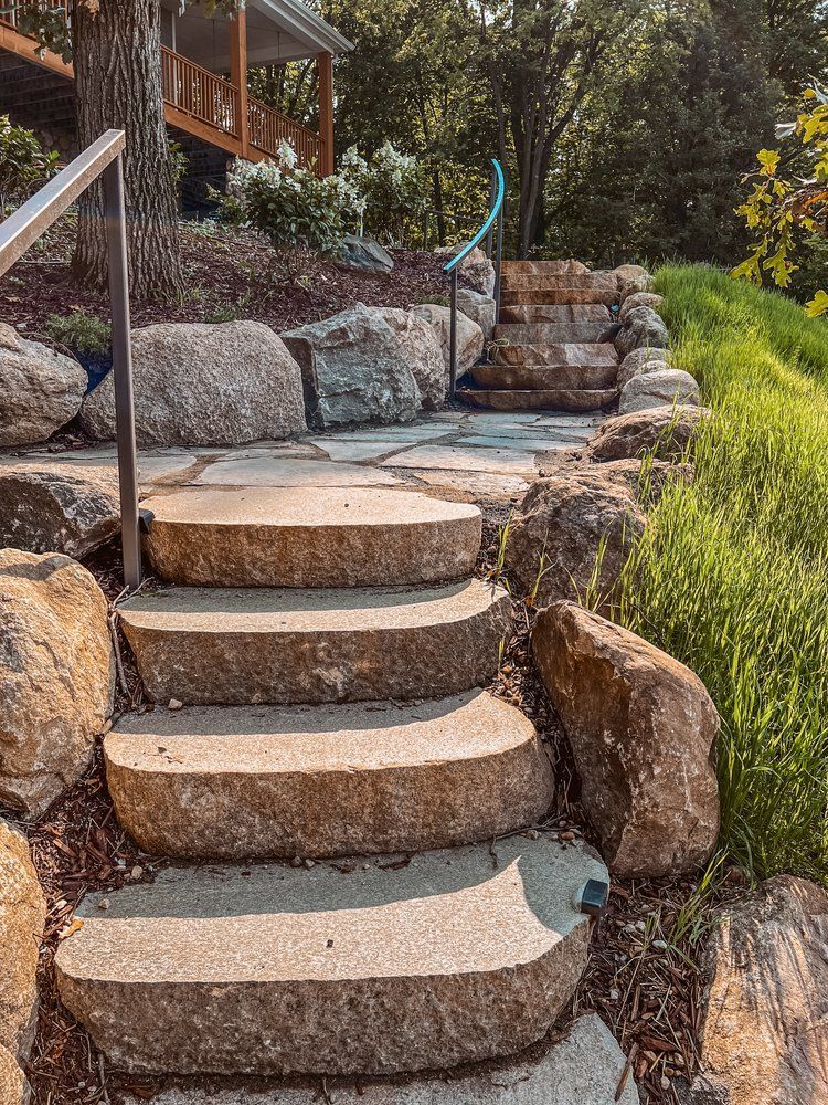 A set of stone stairs leading up to a house surrounded by rocks.
