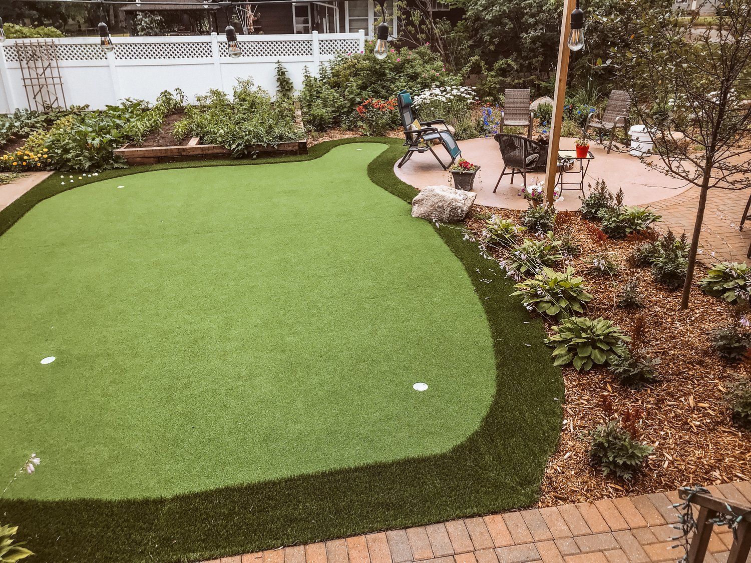 There is a putting green in the middle of the backyard.