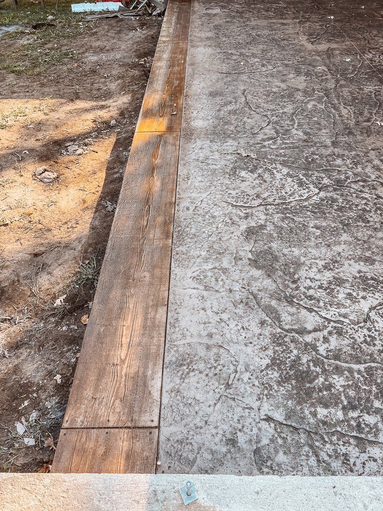 A close up of a concrete driveway with a wooden border.