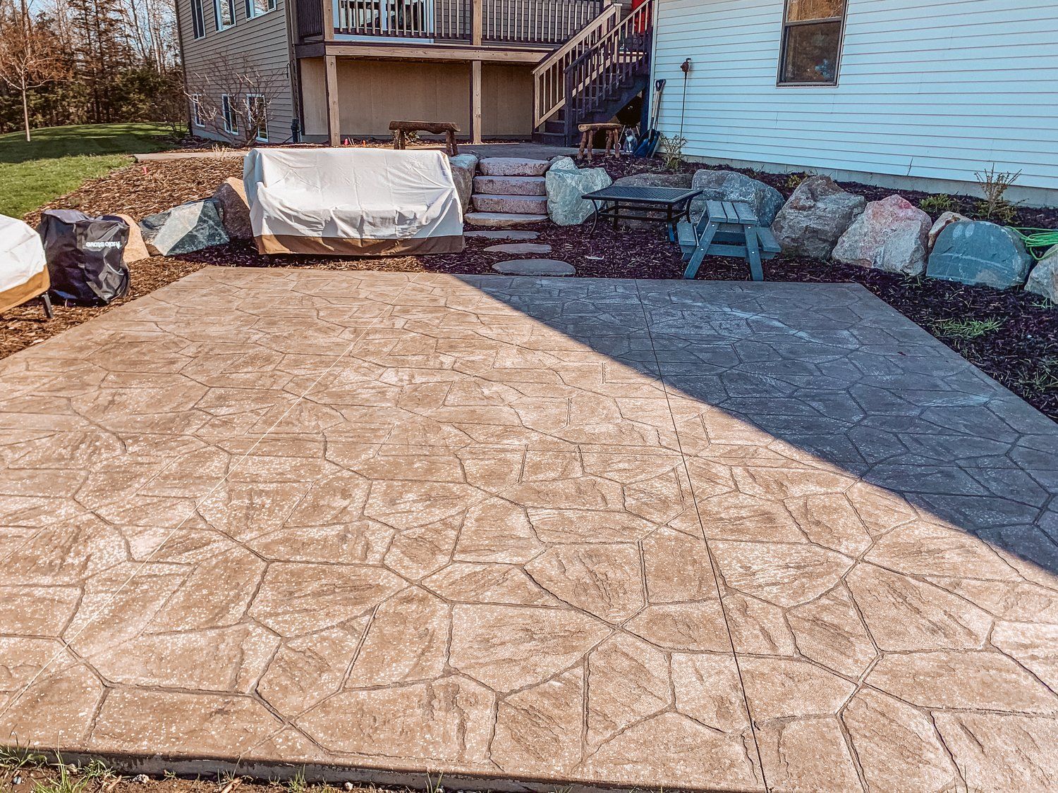 A patio with a grill and stairs in the backyard of a house.