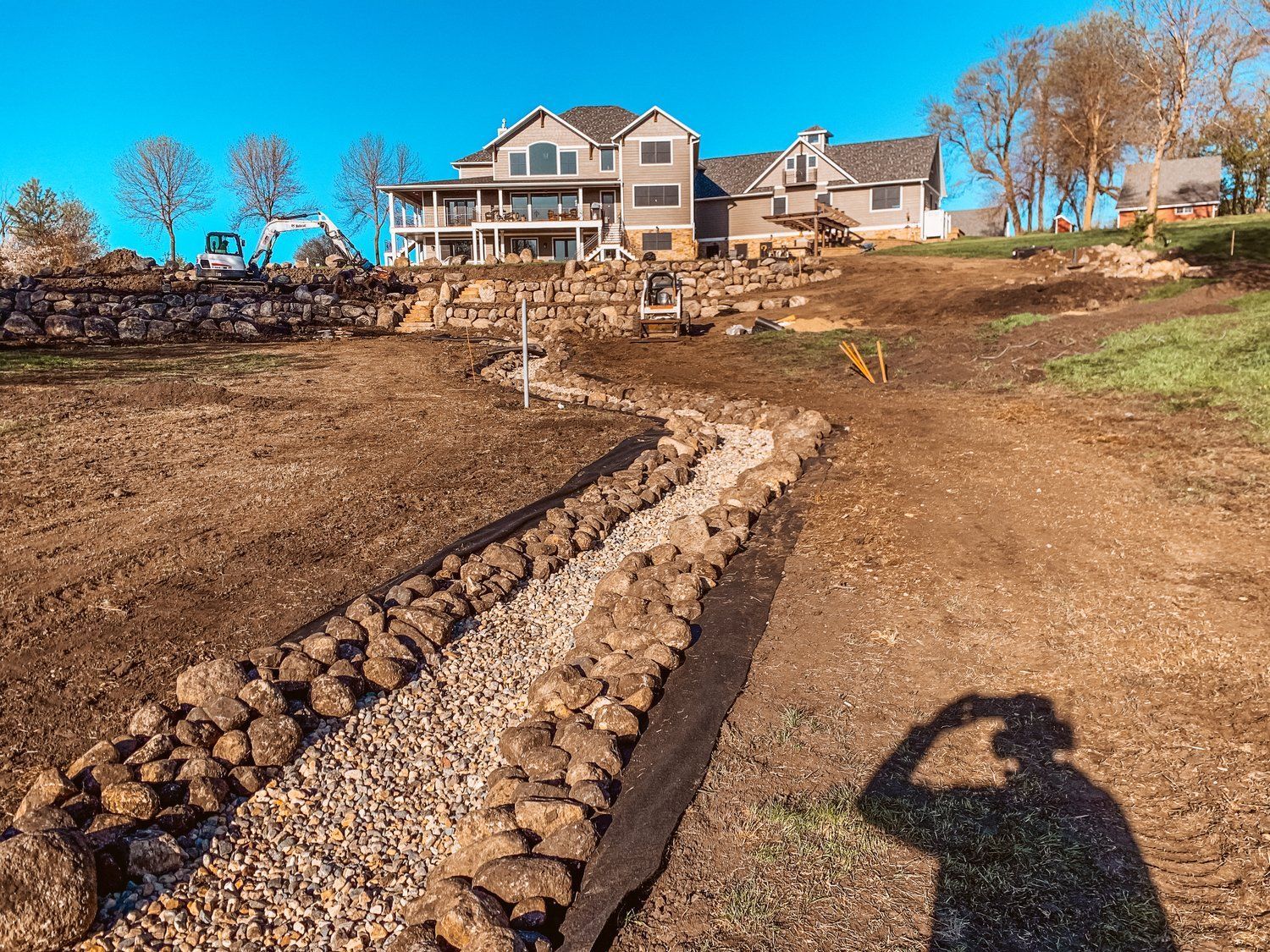 A large house is being built on a hill next to a dirt road.