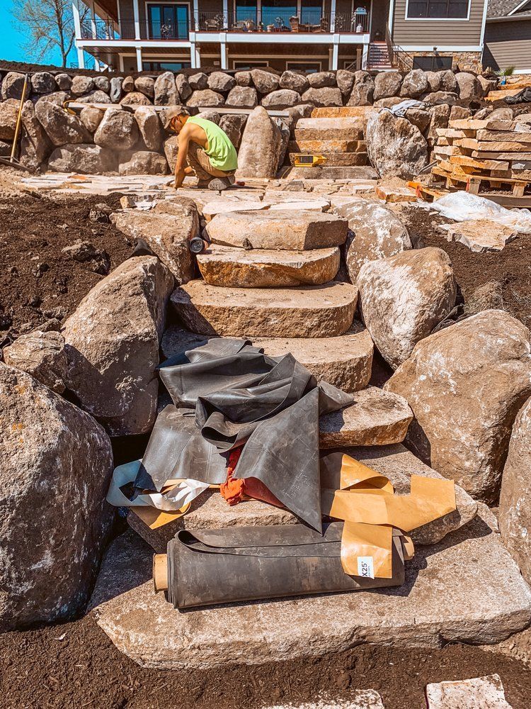 A man is working on a stone staircase in front of a house.