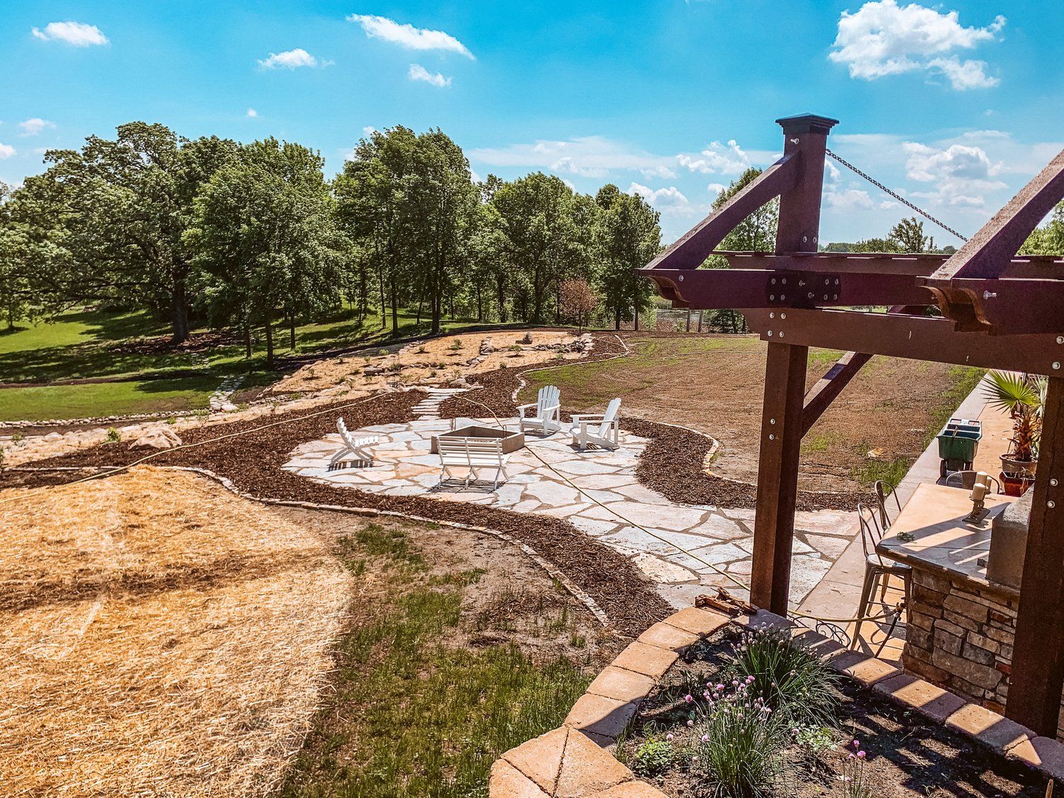 An aerial view of a backyard with a fire pit and a pergola.