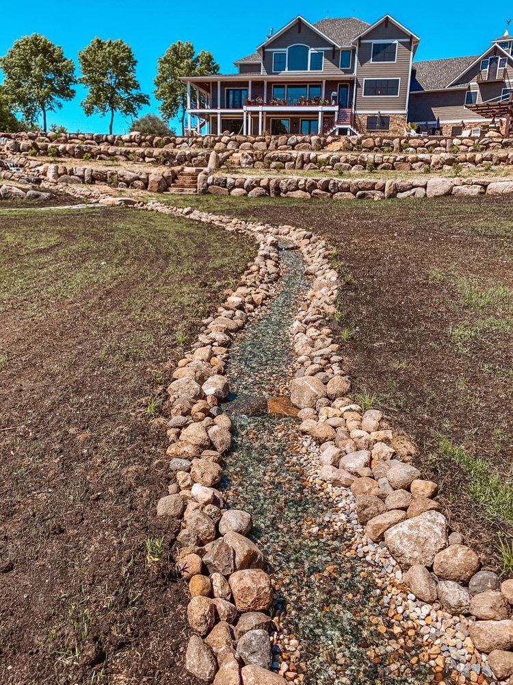 A large house with a stream running through it in front of it.