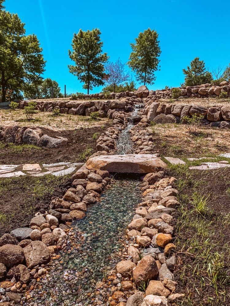 A stream running through a rocky area with trees in the background.