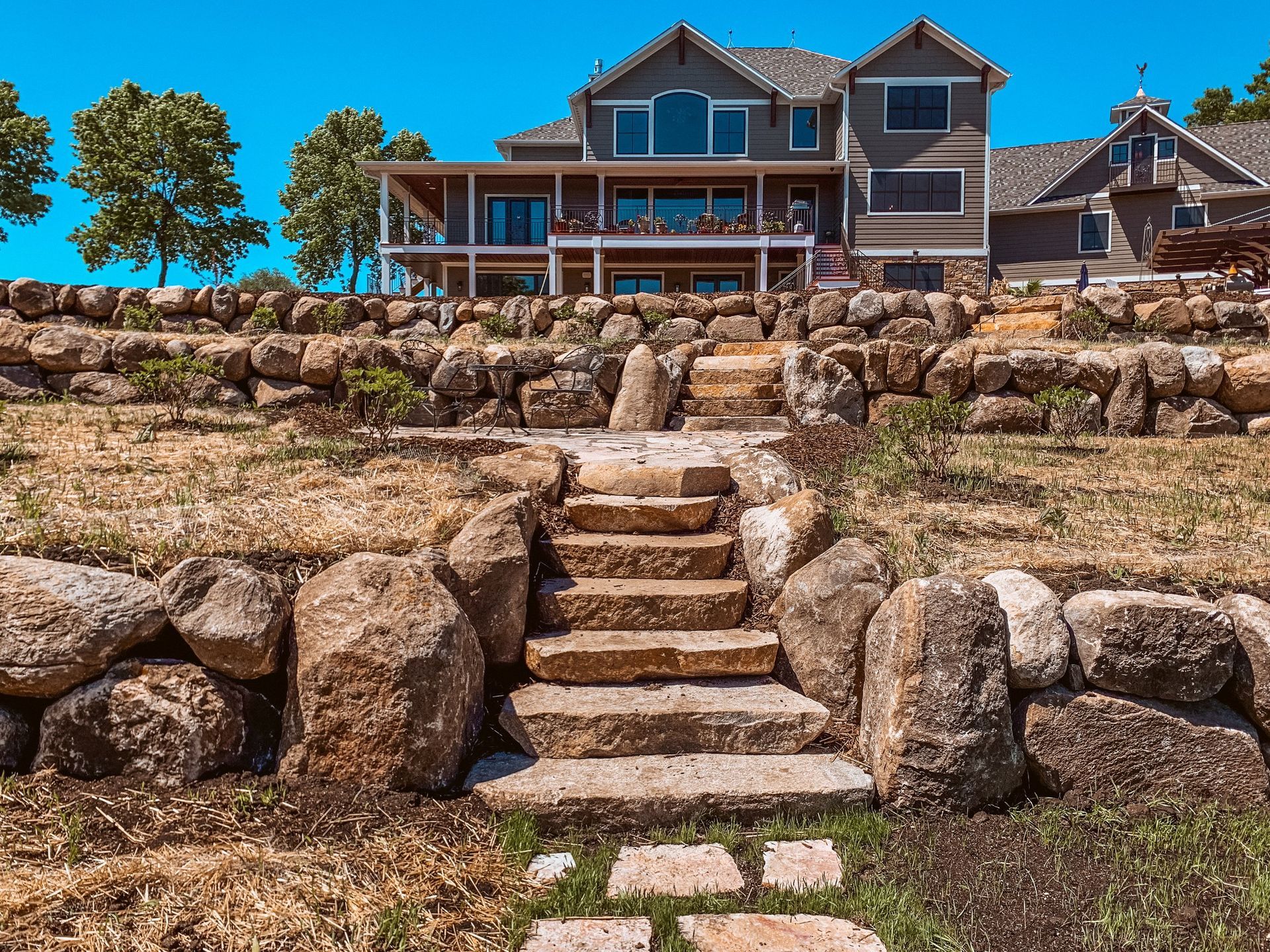 A large house is sitting on top of a hill with stairs leading up to it.