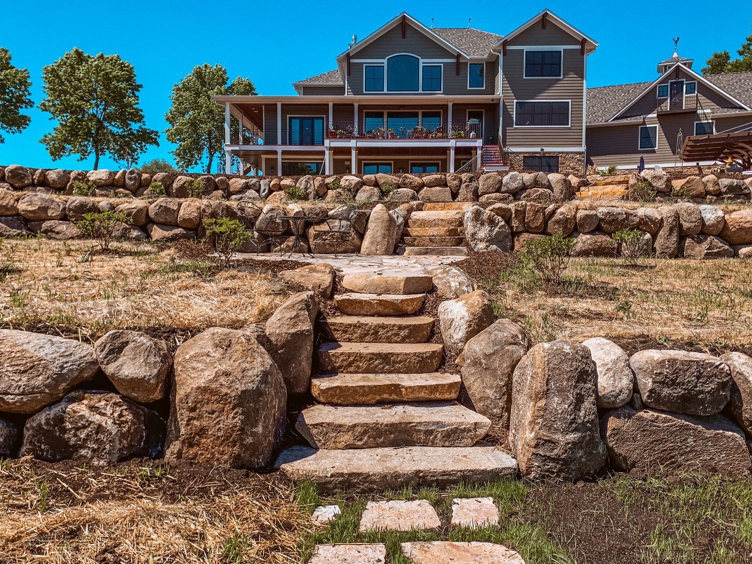 A large house is sitting on top of a hill with stairs leading up to it.