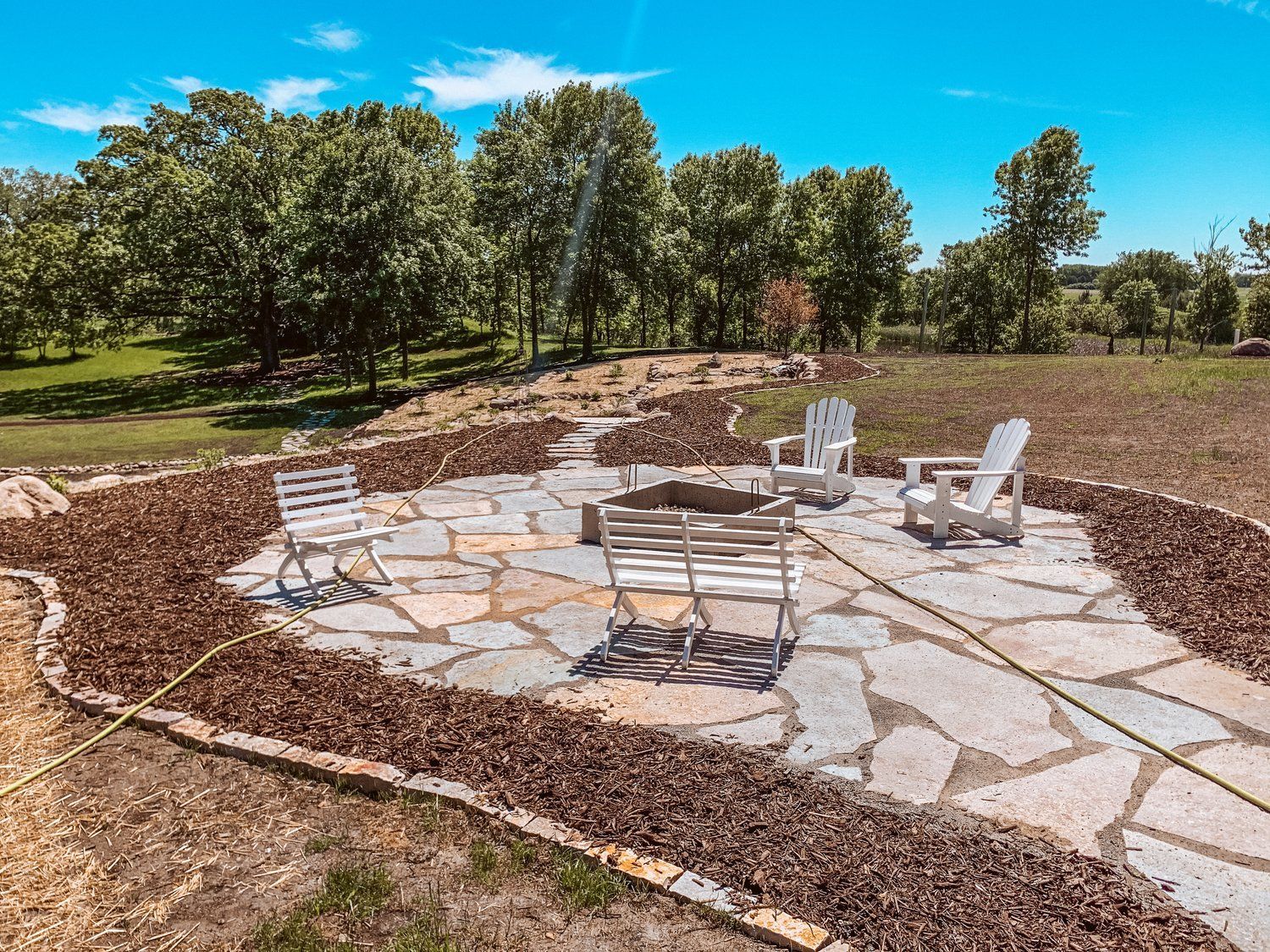 A patio with chairs and a fire pit in the middle of a field.