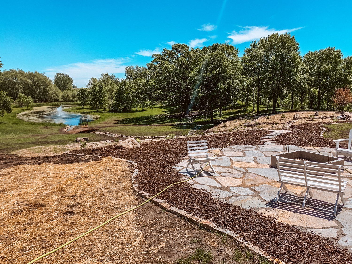 A stone walkway leading to a pond with trees in the background.