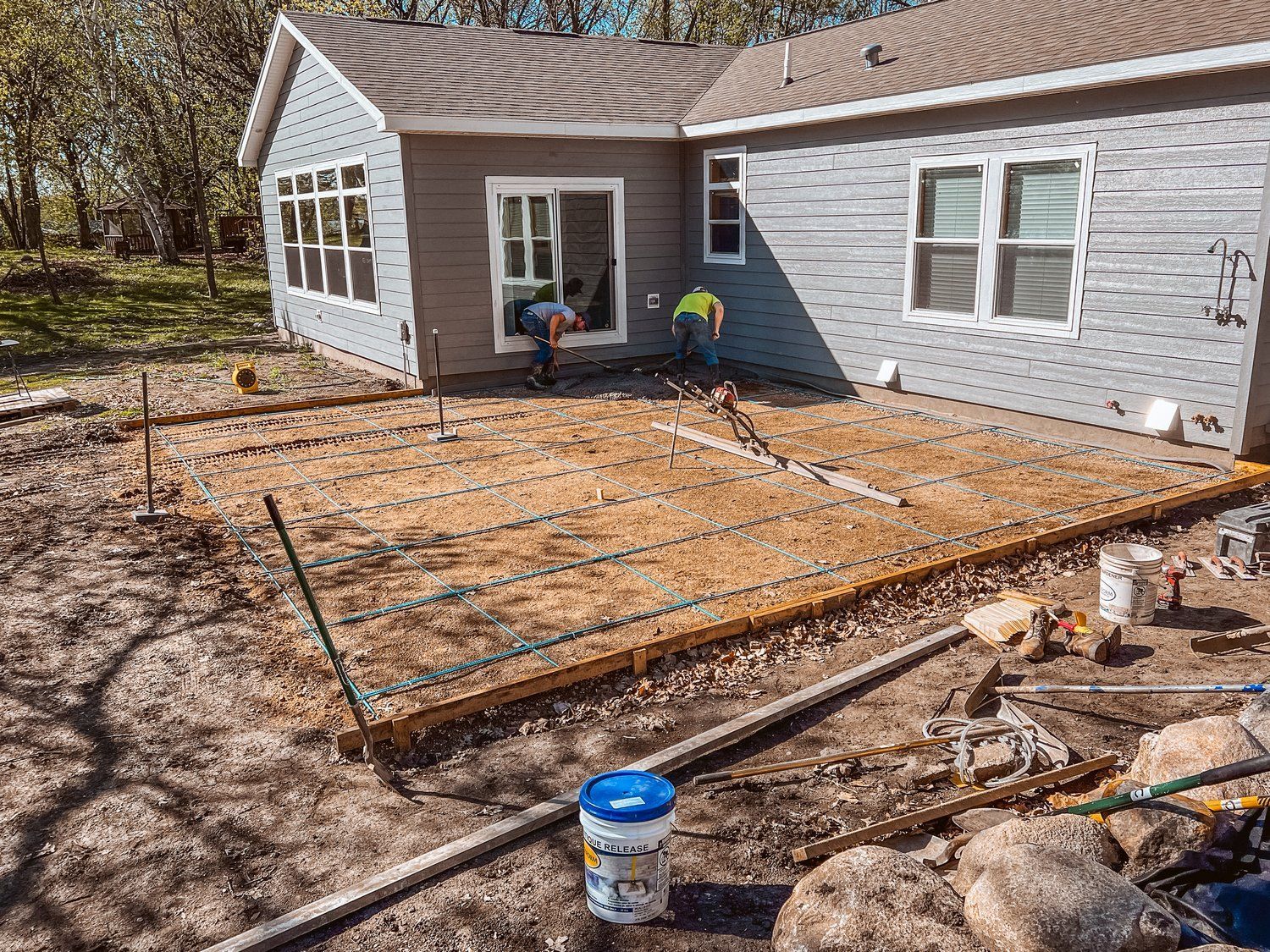A concrete patio is being built in front of a house.
