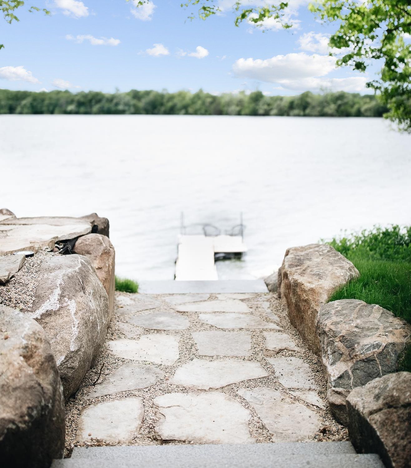 A stone walkway leads to a dock on a lake