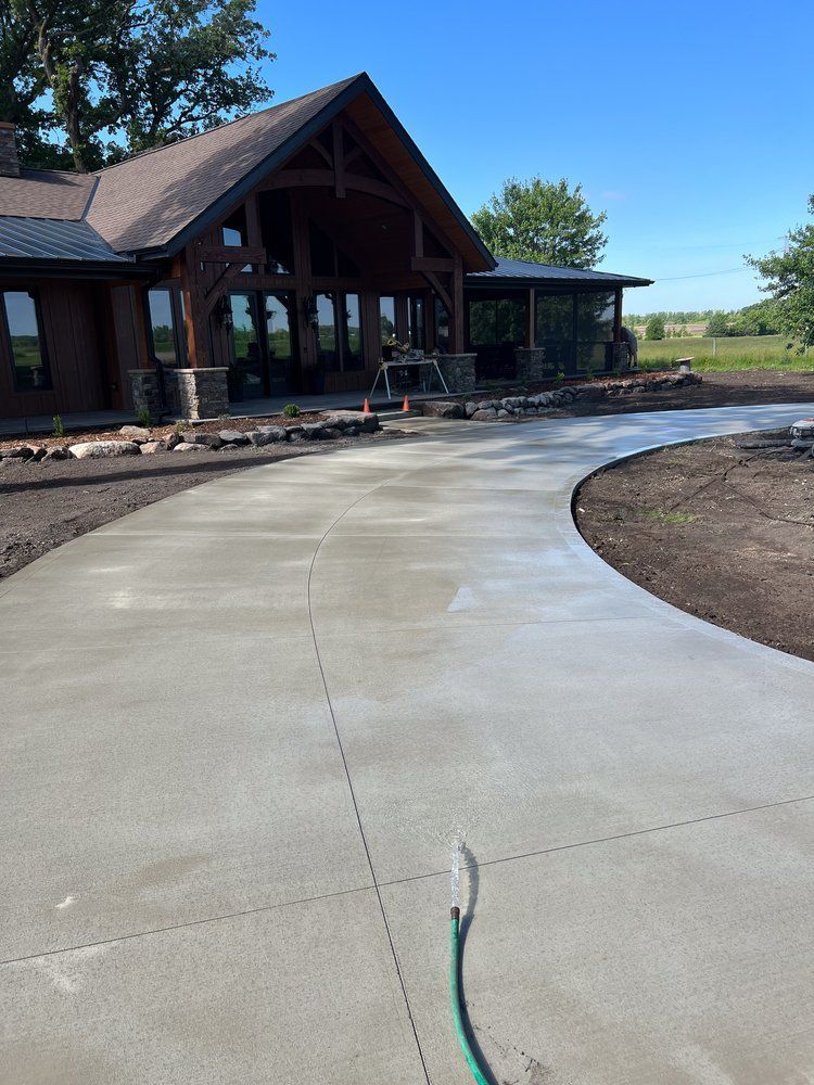 A hose is laying on a concrete driveway in front of a house.