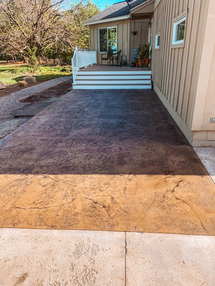 A concrete driveway leading to a house with a porch.
