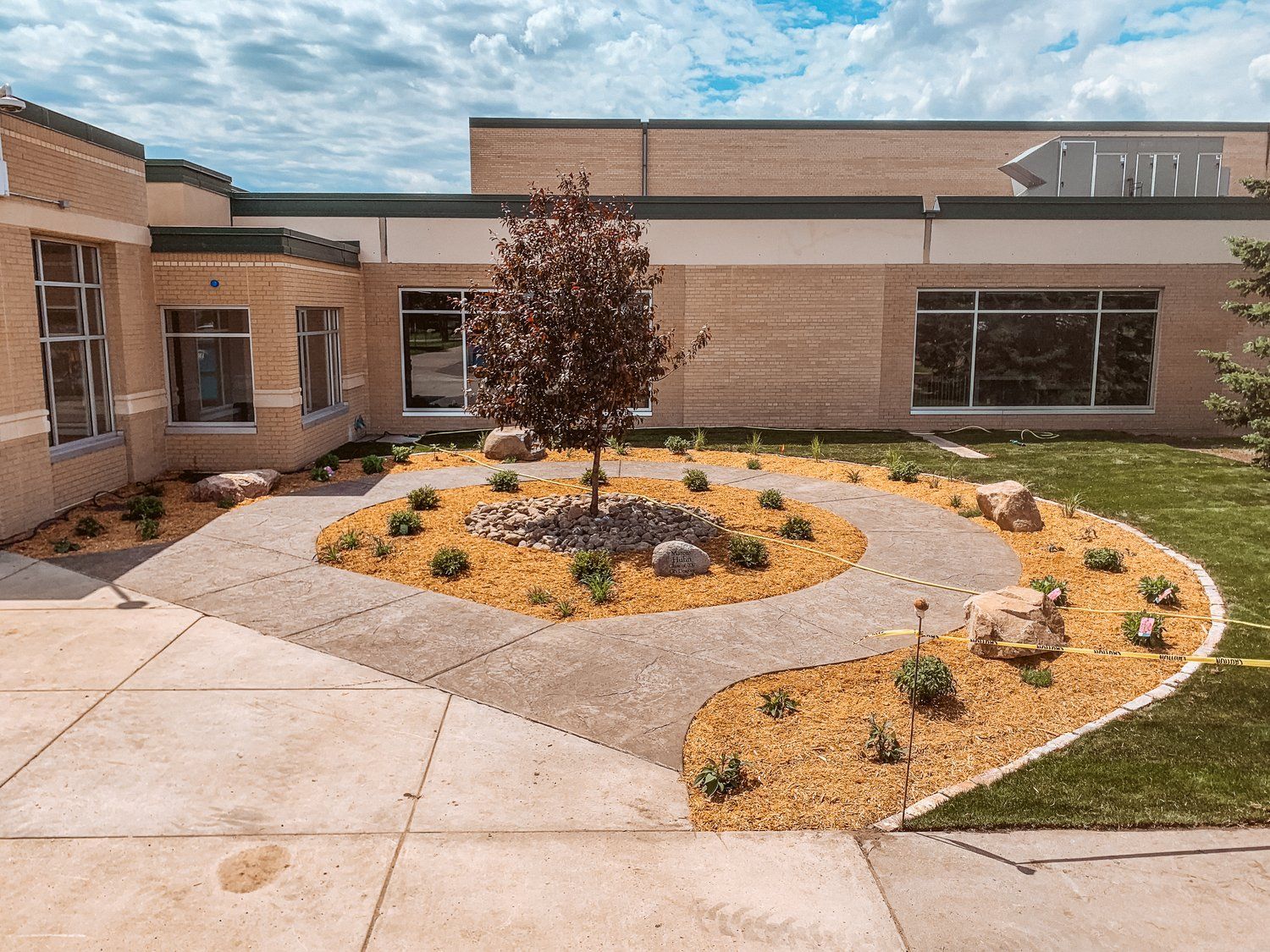 There is a tree in the middle of the courtyard in front of a building.