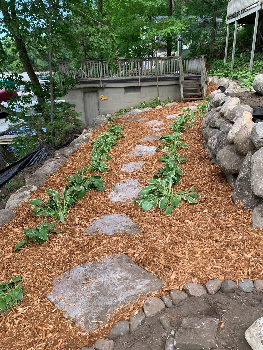 A stone walkway surrounded by mulch and rocks leading to a house.